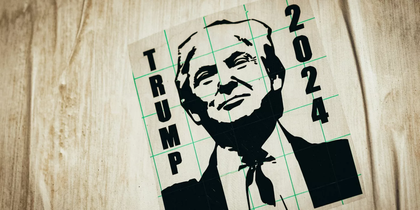 Image shows a black and white poster of Donald Trump promoting him for the 2024 US Presidential Election