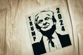 Image shows a black and white poster of Donald Trump promoting him for the 2024 US Presidential Election